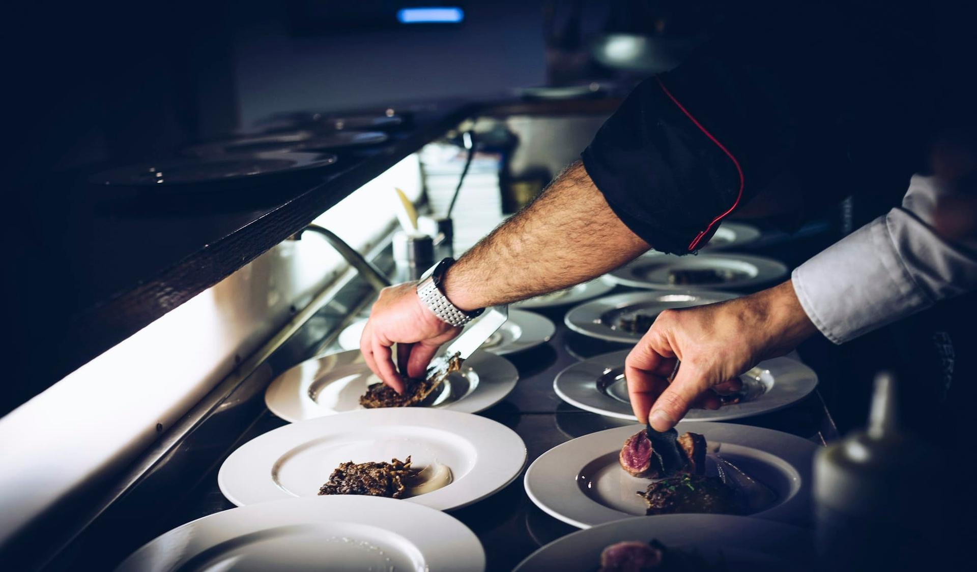 A chef adding final touches to a row of plated dishes