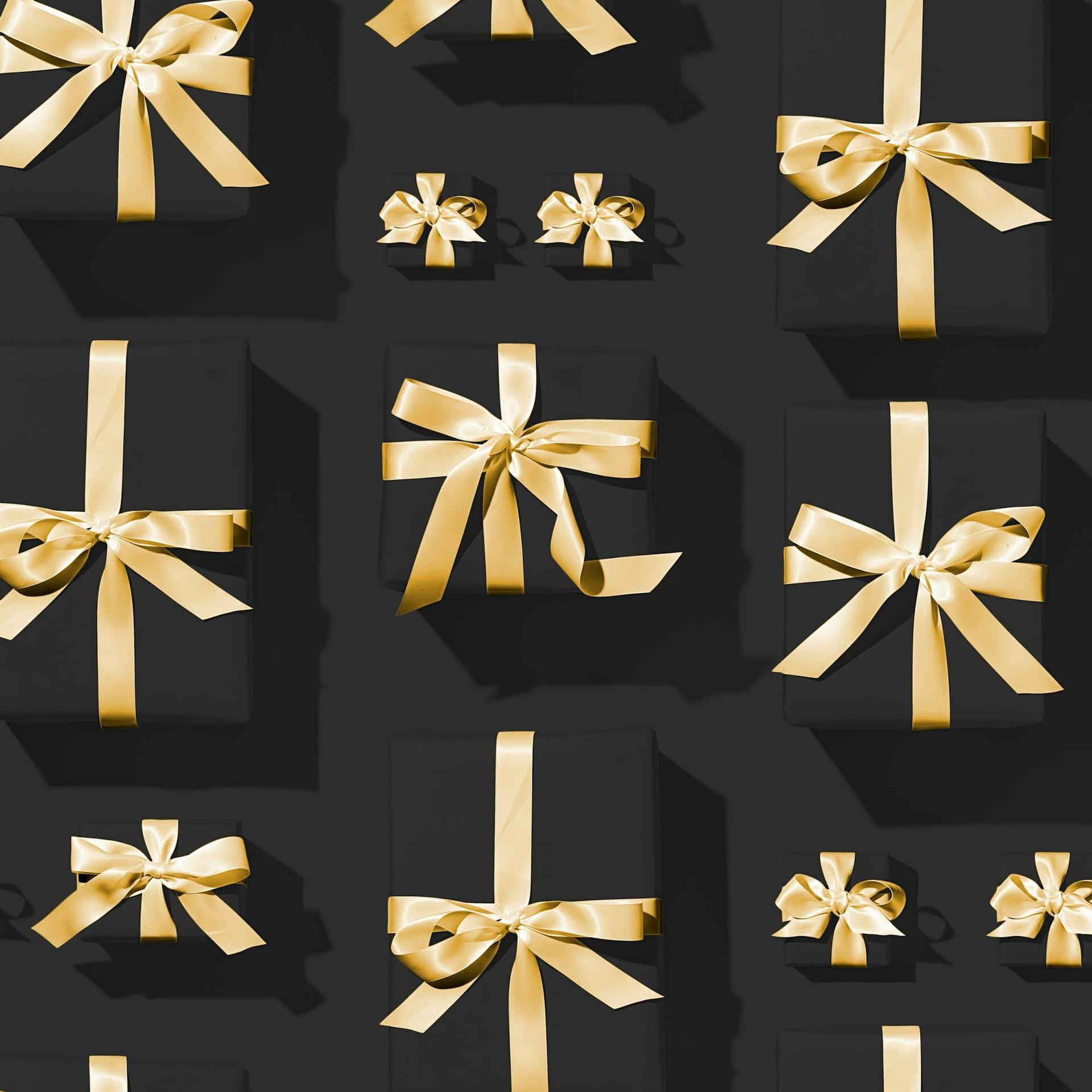Black gift boxes tied with gold satin bows, viewed from above