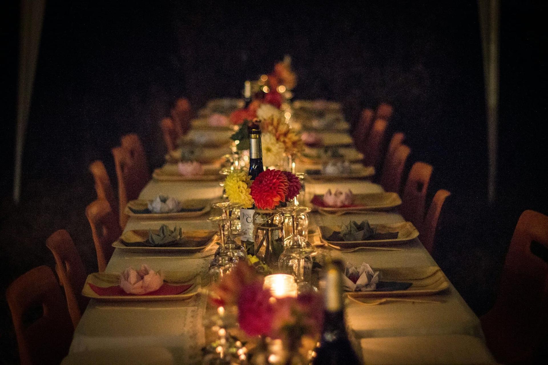 A long banquet table set with flowers and candlelight in a darkened dining room