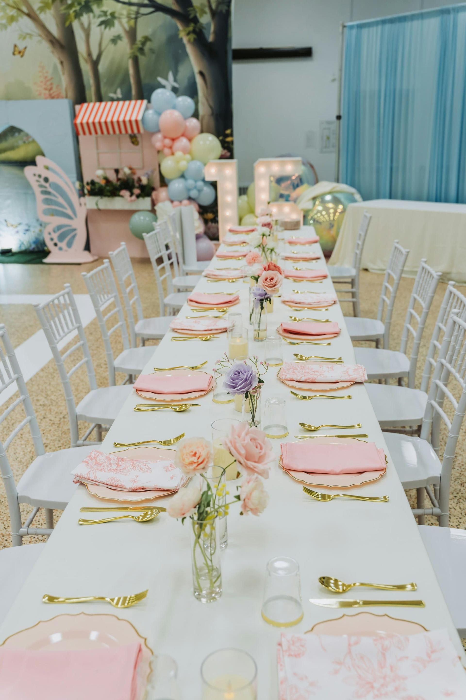 A long celebration table with pastel décor and gold cutlery
