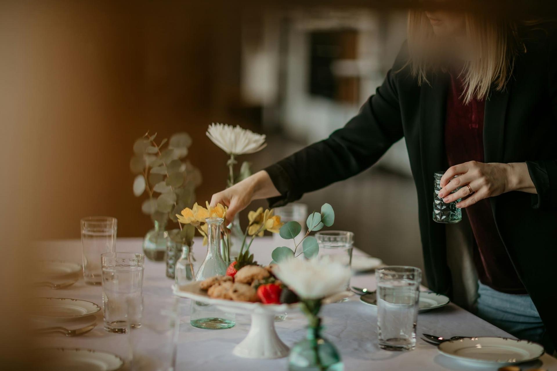 A stylist arranging flowers on a dressed dining table